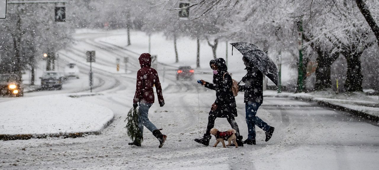 Heavy snow falls as people wearing face masks to curb the spread of COVID-19 cross a road in Burnaby, B.C., on Monday, December 21, 2020.  THE CANADIAN PRESS/Darryl Dyck