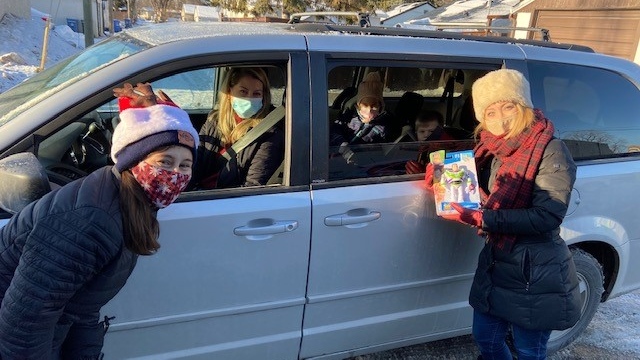 CTV's Colleen Bready (right) and Bounce FM's Mandy Shew (left) accept a toy from donors who are helping the Toy Mountain initiative on Dec. 3, 2021. (Source: Colleen Bready/ CTV News Winnipeg) 