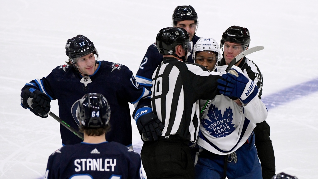 Toronto Maple Leafs' Wayne Simmonds (24) is held back by officials as he tries to get to Winnipeg Jets' Logan Stanley (64) during the third period of NHL action in Winnipeg on Sunday December 5, 2021. THE CANADIAN PRESS/Fred Greenslade 