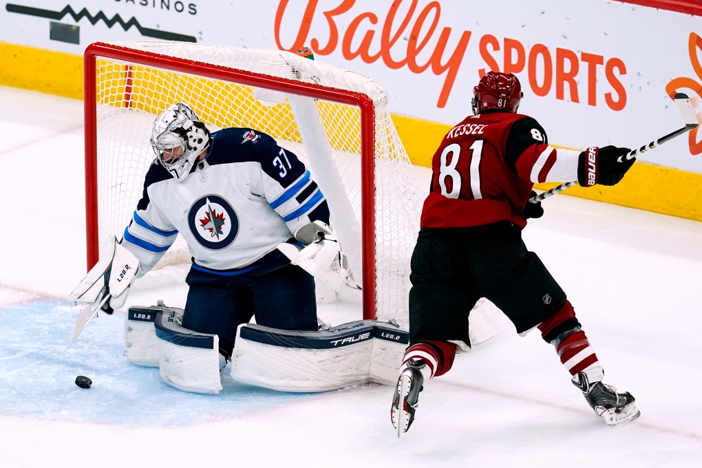 Winnipeg Jets goaltender Connor Hellebuyck (37) makes a save on a shot by Arizona Coyotes right wing Phil Kessel (81) during the first period of an NHL hockey game Tuesday, Jan. 4, 2022, in Glendale, Ariz. (AP Photo/Ross D. Franklin) 