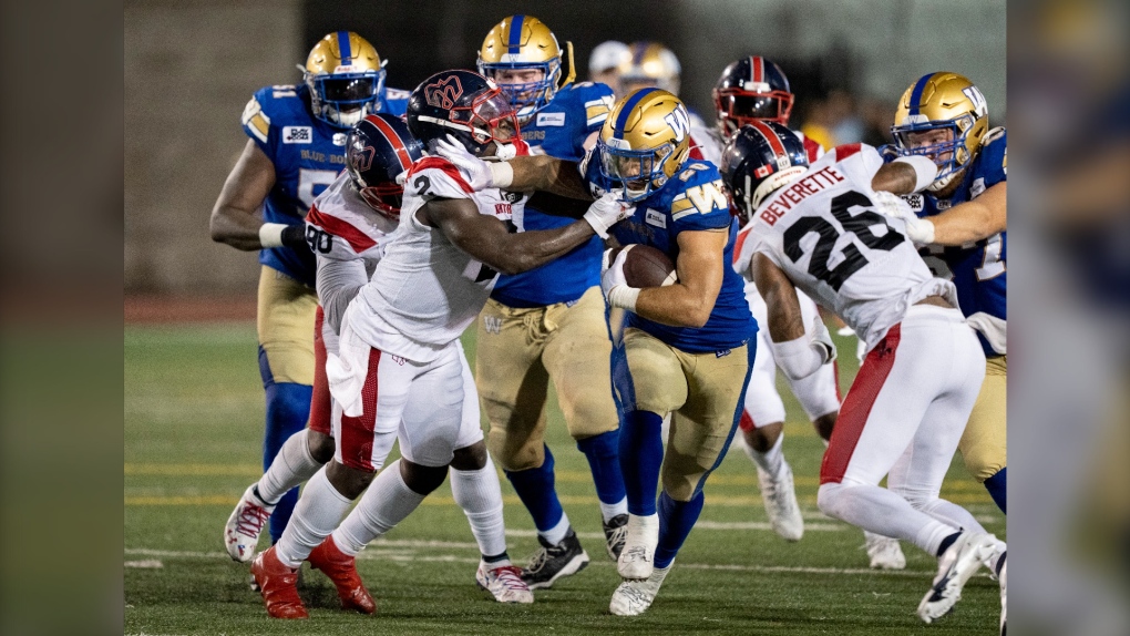 Winnipeg Blue Bombers running back Brady Oliveira fends off Montreal Alouettes linebacker Micah Awe during fourth quarter CFL football action in Montreal on Thursday, August 4, 2022. THE CANADIAN PRESS/Paul Chiasson