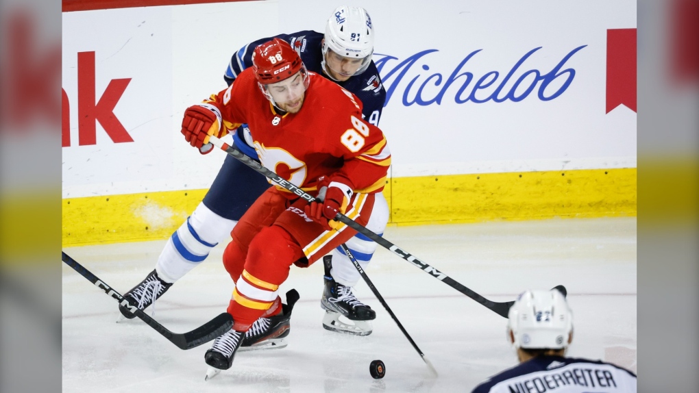 Winnipeg Jets forward Cole Perfetti, right, checks Calgary Flames forward Andrew Mangiapane during second period NHL preseason hockey action in Calgary, Alta., Monday, Oct. 2, 2023. THE CANADIAN PRESS/Jeff McIntosh