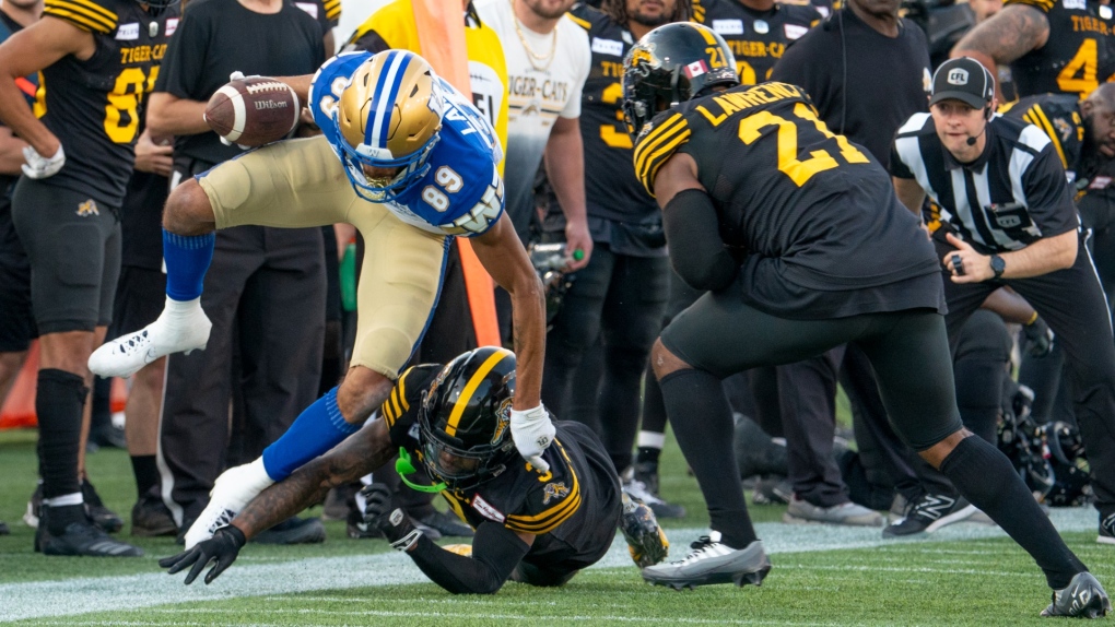 Winnipeg Blue Bombers wide receiver Kenny Lawler (89) is tripped up by Hamilton Tiger Cats defensive back Kenneth George Jr. (3) during second half CFL football game action in Hamilton, Ont., Saturday, Sept. 16, 2023. THE CANADIAN PRESS/Peter Power